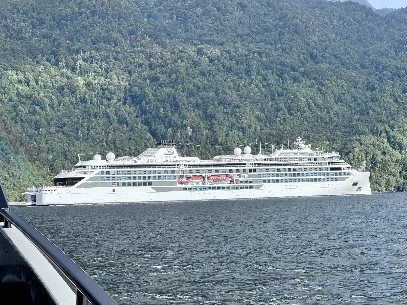 Viking Octantis in the chilean fjords with green lined cliffs behind the ship