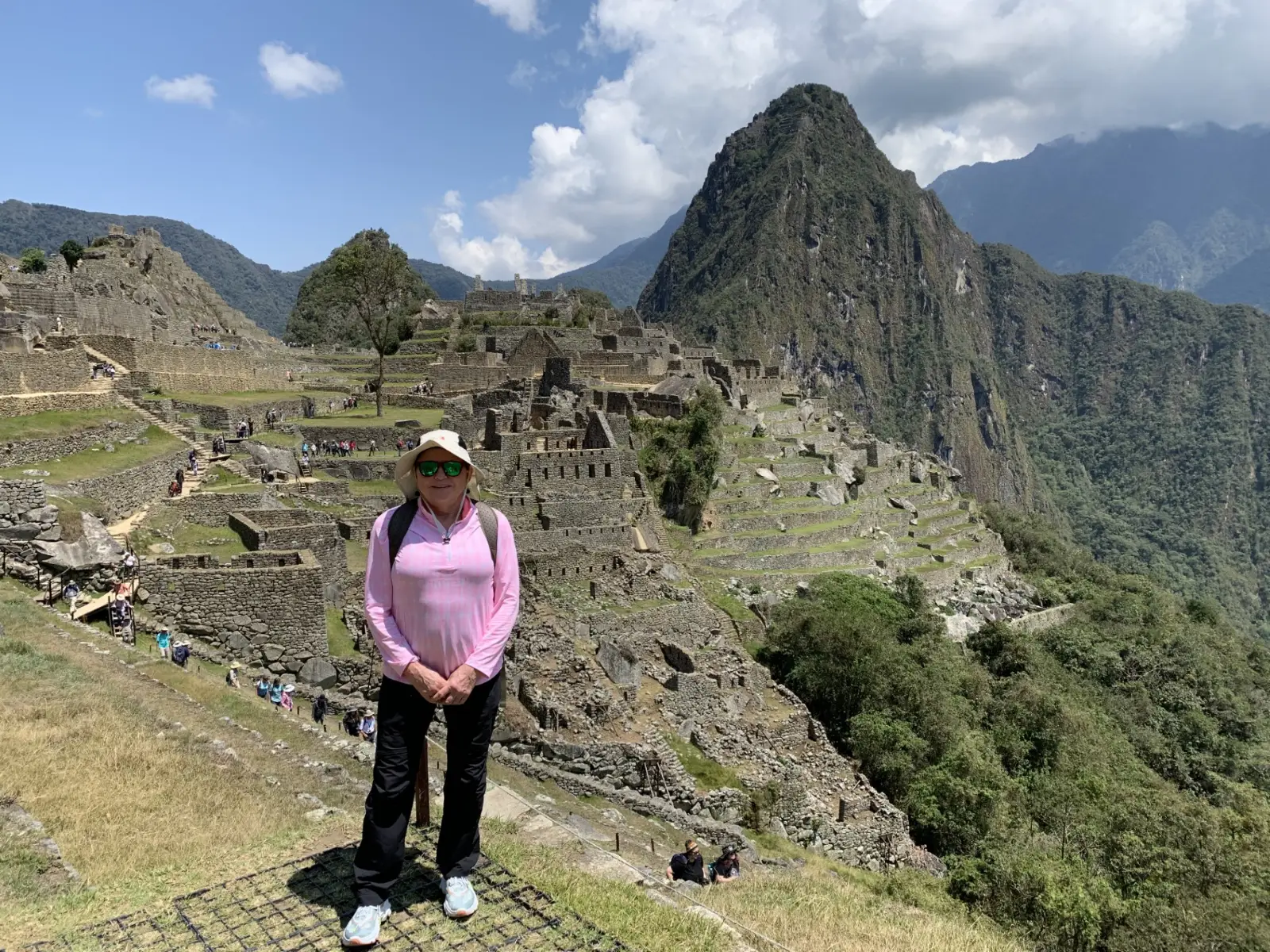 Susan in pink long sleeved SPF style shirt standing at the Machu Picchu site in Peru