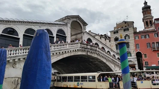 Venice's Rialto Bridge over the Grand Canal, with a vaporetto and gondolas passing beneath